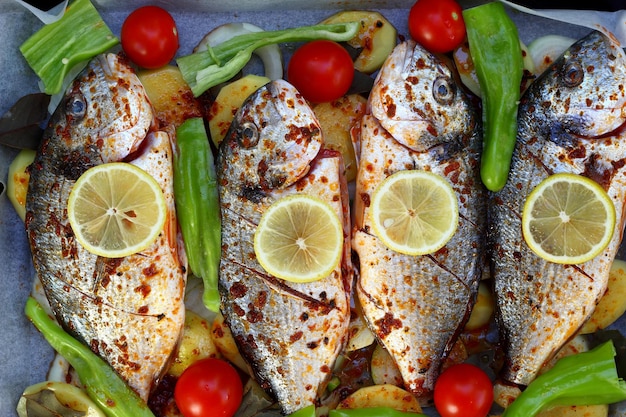 Pesce marino al forno dorado o orzo marino con peperoncino, pomodoro, olive e cipolla