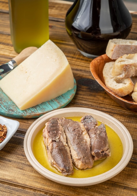 Pesce, olio d'oliva, parmigiano, pane e vino su un tavolo di legno. Cucina mediterranea