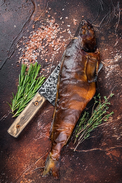 Pesce persico affumicato caldo o lucioperca su una tavola di legno con erbe aromatiche. Sfondo scuro. Vista dall'alto.