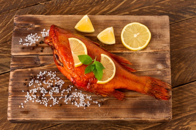 Pesce persico affumicato delizioso dell'oceano sul tagliere di legno per alimento sano, dieta o concetto di cottura, fuoco selettivo.