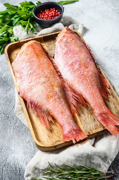 Pesce persico crudo in una ciotola di legno con prezzemolo