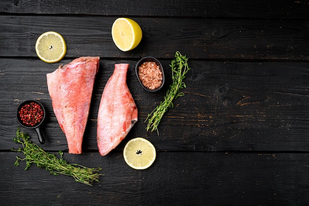 Pesce persico rosso crudo o branzino su sfondo nero tavolo in legno vista dall'alto piatto con spazio di copia per testo