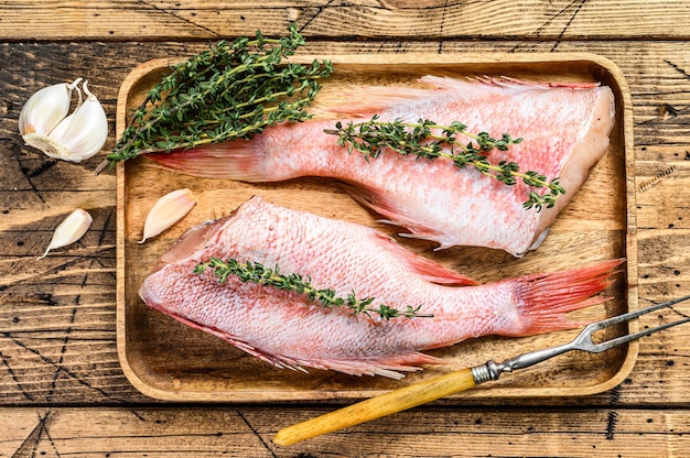 Pesce persico rosso intero crudo o branzino su un piatto