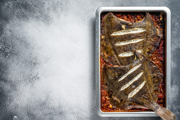 Pesce piatto passera di mare arrosto in salsa di pomodoro nella teglia. Vista dall'alto.