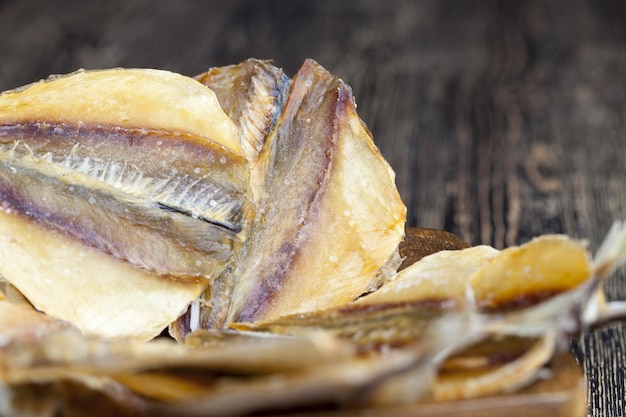 Pesce piccolo essiccato e macellato su un tavolo di legno, pesce piccolo eviscerato ed essiccato con sale