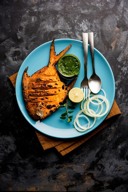 Pesce Pomfret Tandoori cotto in un forno di argilla e guarnito con insalata di limone, menta, cavolo e carote. Messa a fuoco selettiva