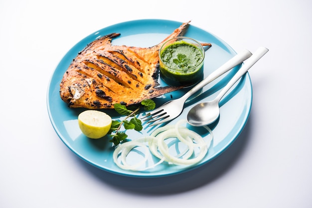 Pesce Pomfret Tandoori cotto in un forno di argilla e guarnito con insalata di limone, menta, cavolo e carote. Messa a fuoco selettiva