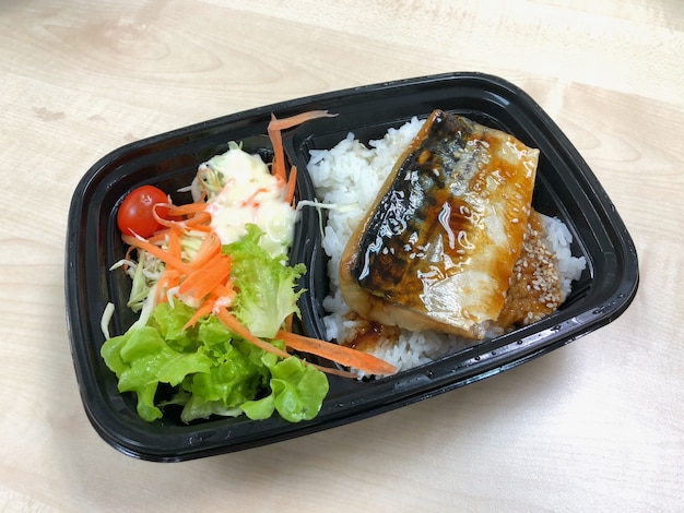 Pesce Saba grigliato con salsa teriyaki sulla ciotola di riso sormontato nel contenitore di plastica