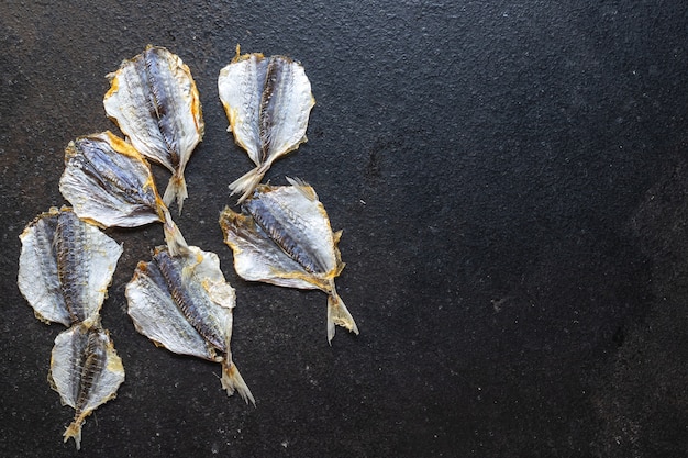 Pesce salato piccolo spuntino essiccato al sole o affumicato sul tavolo copia spazio cibo sfondo