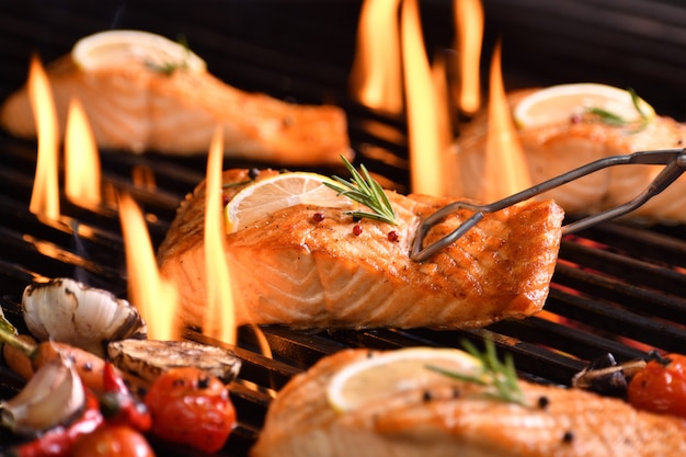 Pesce salmone alla griglia con verdure varie sulla griglia ardente