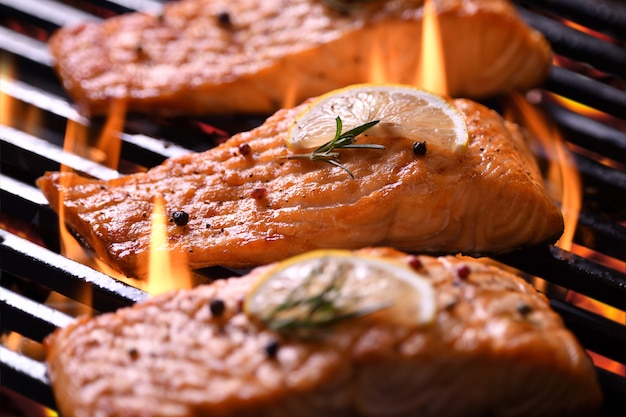 Pesce salmone alla griglia con verdure varie sulla griglia ardente