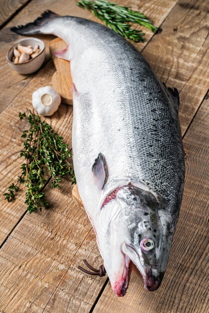 Pesce salmone marino crudo su un tavolo da cucina in legno con erbe aromatiche. Fondo in legno. Vista dall'alto.