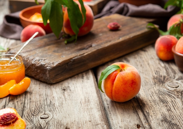 Pesche di natura morta sulla tavola di legno con il coltello del tagliere in pesche mature succose della chiave scura