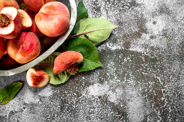 Pesche fresche in una ciotola su un fondo rustico