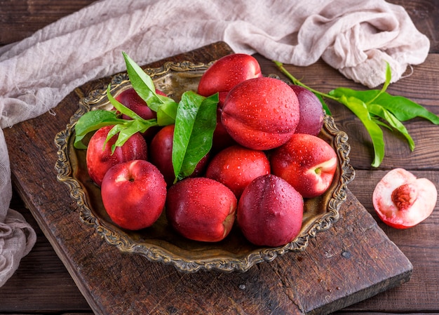 Pesche mature rosse nettarine in un piatto di ferro