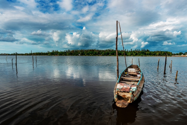 Peschereccio e barriera e fiume dell'acqua con la tempesta del cielo della nuvola