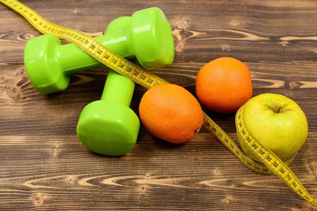 Peso dei manubri con nastro di misurazione e mela arancione per il concetto di dieta