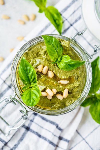 Pesto di basilico con noci in un barattolo di vetro, vista dall'alto.