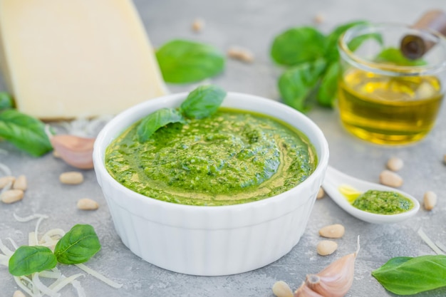 Pesto di basilico tradizionale italiano in una ciotola bianca con ingredienti per cucinare Spazio di copia