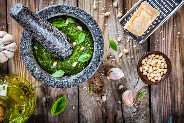 Pesto fatto in casa basilico parmigiano pinoli aglio olio d'oliva su tavola di legno