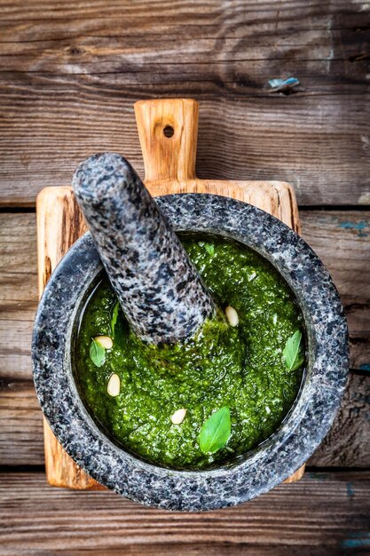 Pesto fatto in casa in un mortaio su fondo di legno