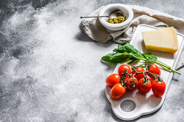 Pesto in mortaio di marmo, foglie di basilico e parmigiano su un tagliere.