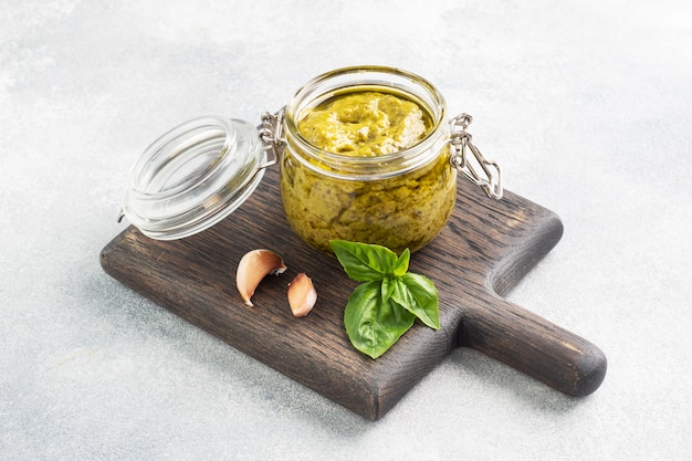 Pesto in vasetto di vetro, foglie di basilico fresco e aglio. copia spazio