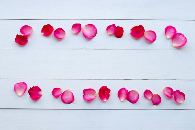 Petali di rosa su fondo di legno bianco.