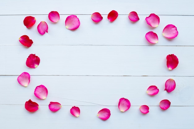 Petali di rosa su fondo di legno bianco.