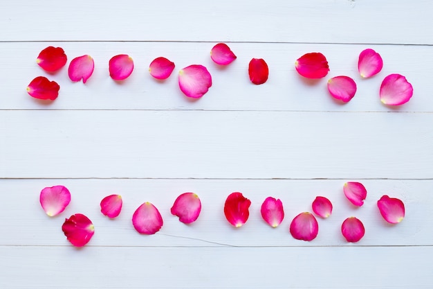 Petali di rosa su fondo di legno bianco.