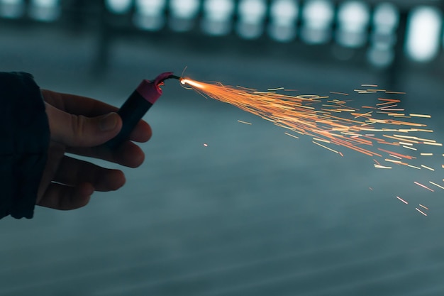 Petardo in fiamme con scintille ragazzo che tiene un petardo in una mano