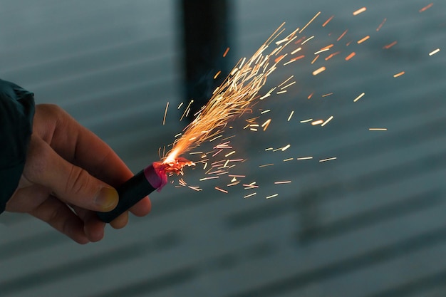 Petardo in fiamme con scintille ragazzo che tiene un petardo in una mano