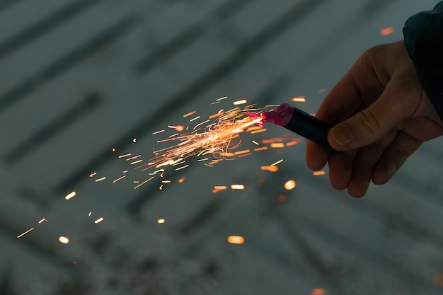 Petardo in fiamme con scintille ragazzo che tiene un petardo in una mano