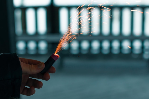 Petardo in fiamme con scintille ragazzo che tiene un petardo in una mano