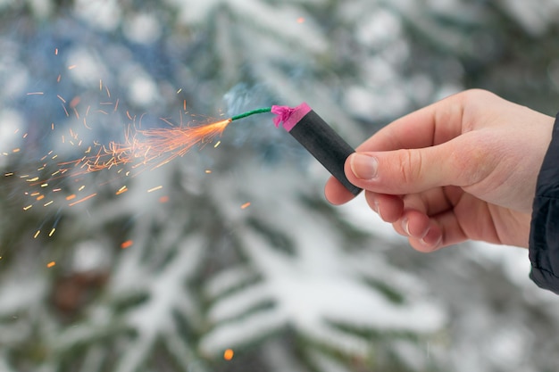 Petardo in fiamme in una mano scintille e fumo di petardo