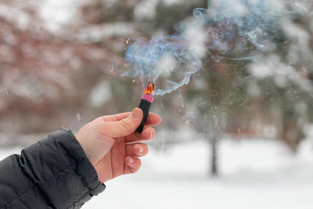 Petardo in fiamme in una mano scintille e fumo di petardo