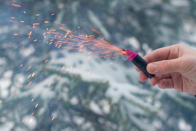 Petardo in fiamme in una mano scintille e fumo di petardo