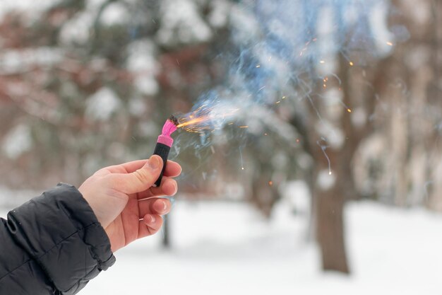 Petardo in fiamme in una mano scintille e fumo di petardo