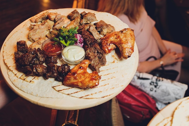 Petti di pollo alla griglia e diverse verdure e funghi cotti su un barbecue servito su tavola di legno Vista ravvicinata Concetto cena barbecue estiva fatta in casa