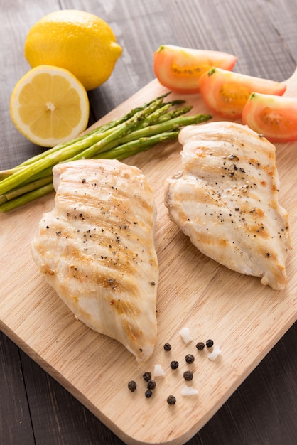 Petti di pollo arrostiti marinati sulla tavola di legno.