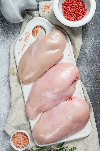 Petti di pollo crudi su un tagliere bianco