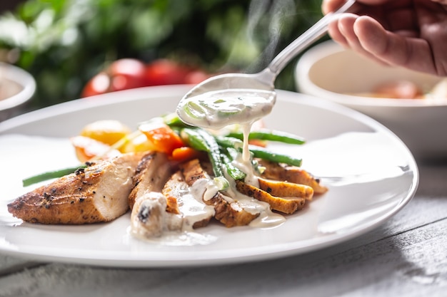 Petti di pollo cucinati con verdure fresche e serviti con salsa di funghi su un piatto.