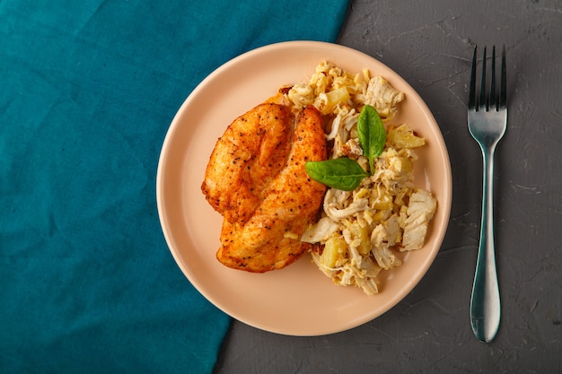 Petto di pollo al forno con insalata su un piatto decorato con spinaci accanto a una forchetta