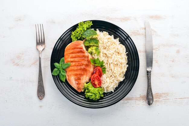 Petto di pollo alla griglia con riso e verdure Cibo sano su un tavolo di legno bianco Vista dall'alto Spazio libero per il testo