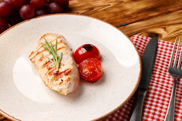 Petto di pollo alla griglia servito con pomodorini sulla fine del tavolo