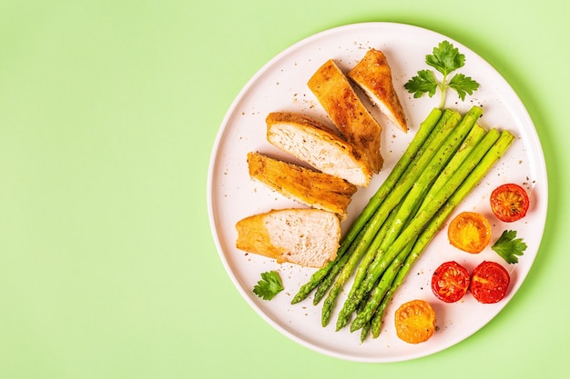 Petto di pollo arrosto con asparagi e pomodori, vista dall'alto.