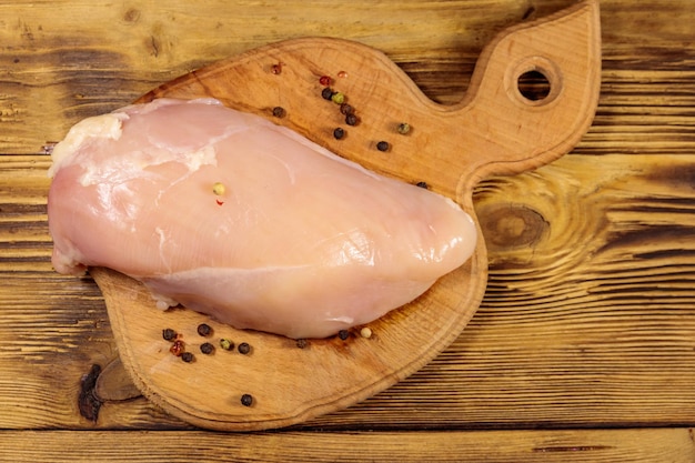 Petto di pollo crudo sul tagliere sulla tavola di legno