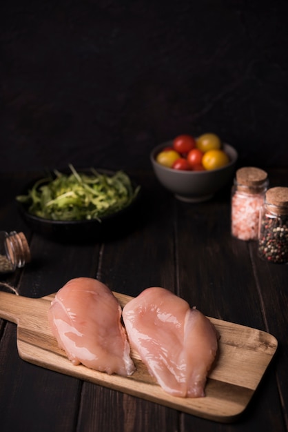 Petto di pollo dell'angolo alto sul bordo di legno con gli ingredienti