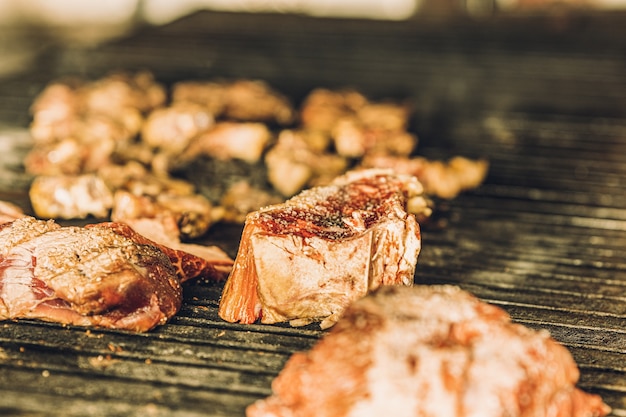 Pezzi crudi di bistecca che cuociono lentamente nella griglia di un ristorante.