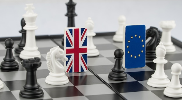 Pezzi degli scacchi e bandiere dell'Unione europea e del Regno Unito su una scacchiera Gioco politico